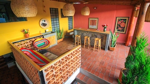 A room with a bed, a small bar area, stools, and potted plants. - Hotel El Andariego (Oaxaca)