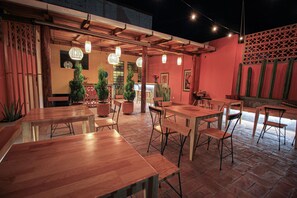 An outdoor dining area with wooden tables and chairs, potted plants, and hanging lights. - Hotel El Andariego (Oaxaca)