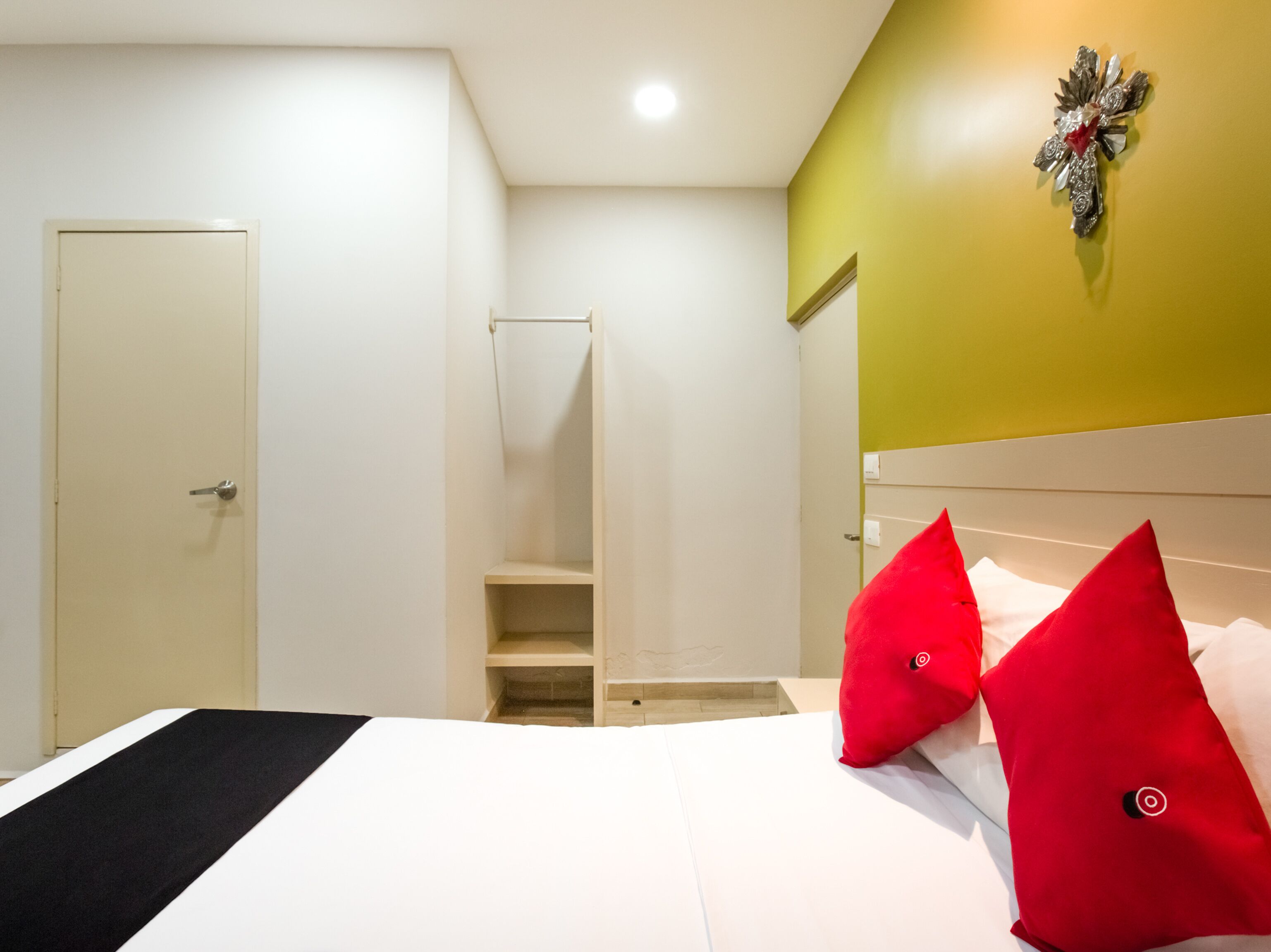 A bedroom with a bed, a wardrobe, a mirror, and a wall decoration.