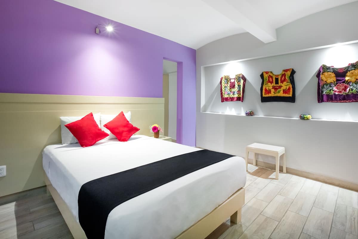 A modern bedroom with a bed, a nightstand, a small table, and decorative pillows.