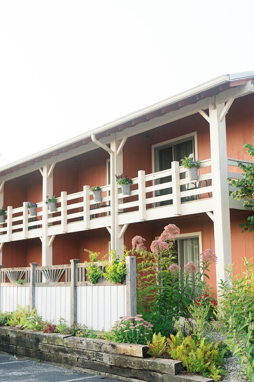 A building with a balcony, potted plants, and a garden area.