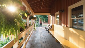 A wooden porch with a bench, potted plants, and a view of the garden. - Brown County Inn (Nashville)