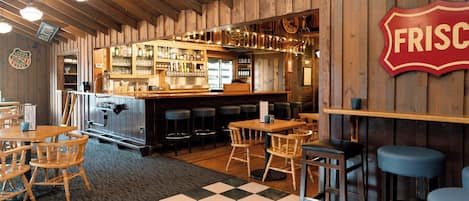 A bar area with wooden walls, a checkered floor, and bar stools.