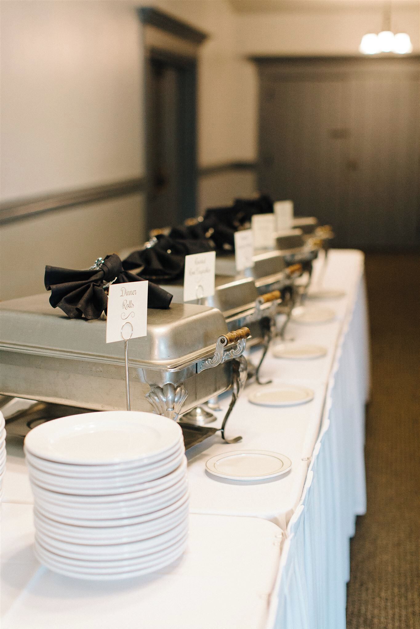 A buffet setup with multiple serving stations, each with a sign indicating the type of food.