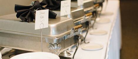 A buffet setup with multiple serving stations, each with a sign indicating the type of food.