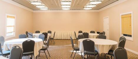 A conference room with multiple tables and chairs, a patterned carpet, and ceiling lights.