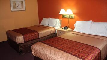 A hotel room with two beds, each with a patterned bedspread, a nightstand with a lamp, and a framed picture on the wall.