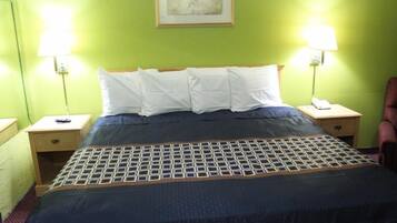 A hotel room with a bed, two bedside tables, a lamp, a chair, and a painting on the wall.