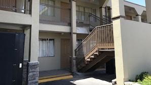 A multi-story building with balconies, a staircase, and a black door. - Hutchinson Inn (Hutchinson)