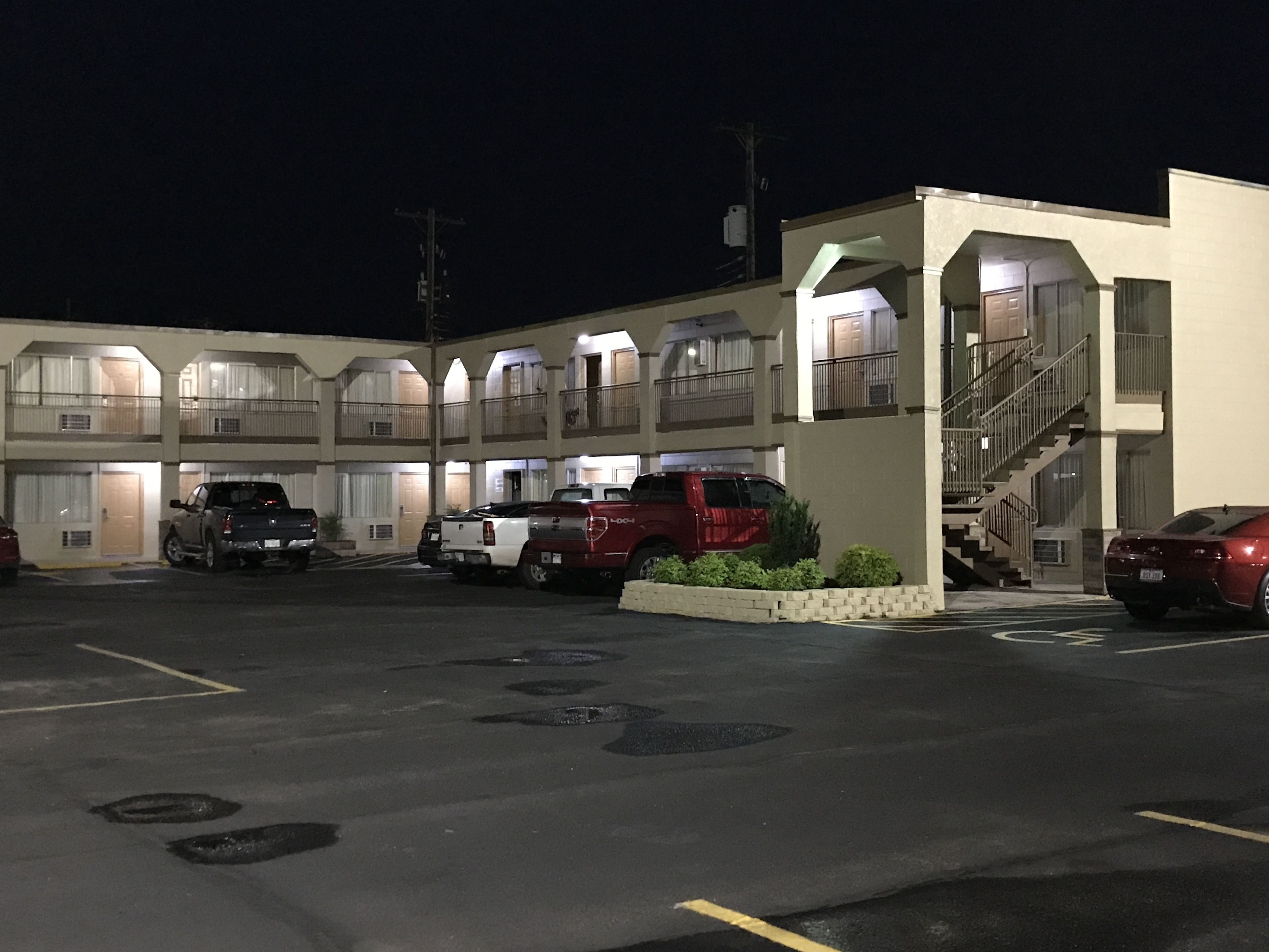 Un motel comprenant plusieurs chambres, un parking et un escalier menant aux étages supérieurs.