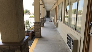 A covered walkway with stone pillars, a yellow line marking, and large windows. - Hutchinson Inn (Hutchinson)