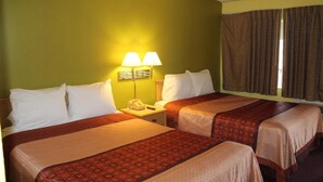 A hotel room with two beds, a nightstand with a lamp, and a window with curtains. - Hutchinson Inn (Hutchinson)