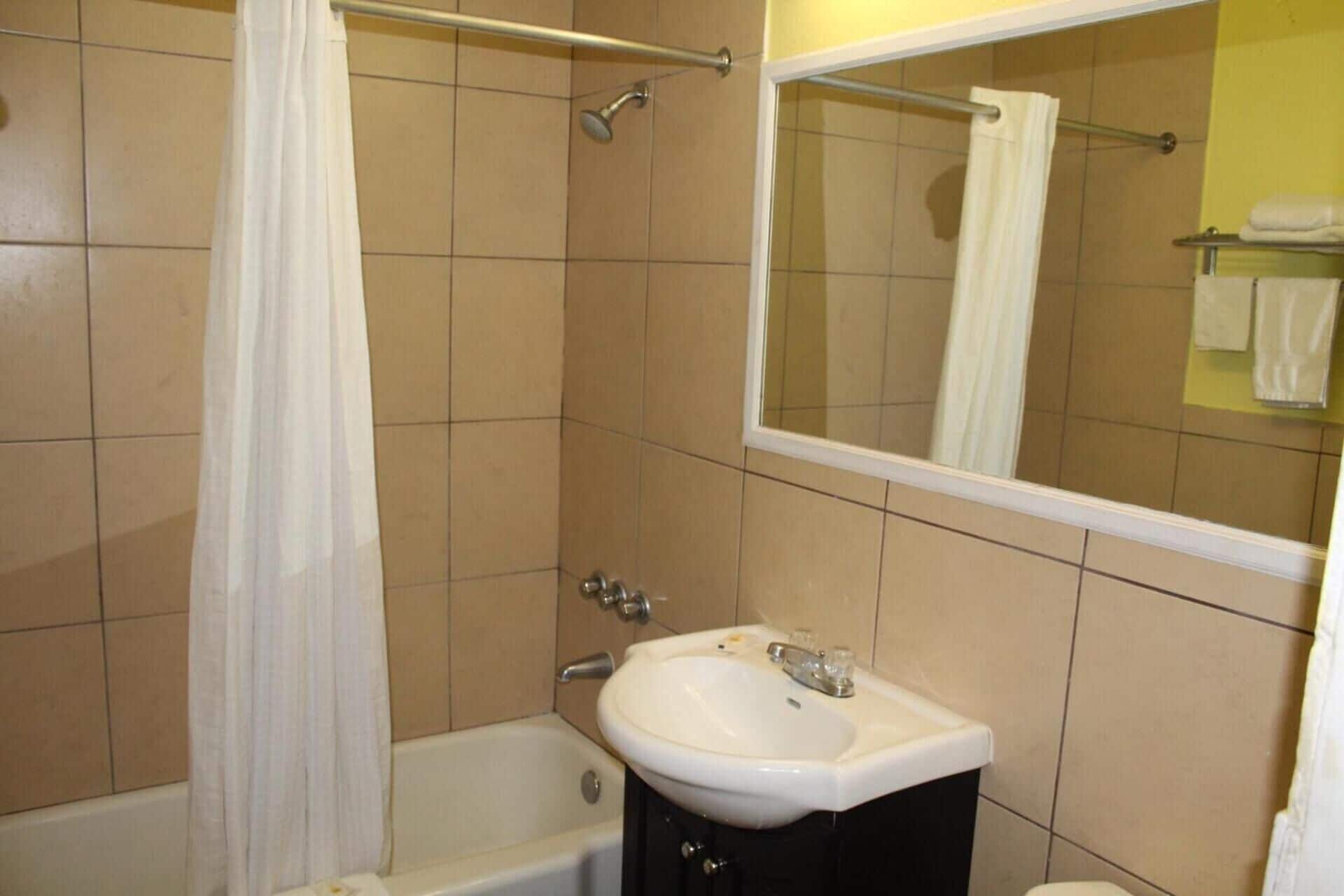A bathroom with a bathtub, a sink, and a mirror.