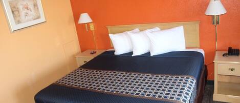 A hotel room with a bed, two bedside tables, a lamp, and a painting on the wall.