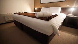 A neatly made bed with white linens, a brown decorative runner, and a rolled white towel. - Neyuki (Kutchan)
