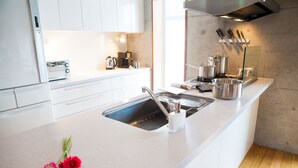 A modern kitchen with white cabinets, a stainless steel sink, and a wooden floor. - Yume Basho (Kutchan)