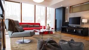 A modern living room with a red sofa, grey armchair, and a large flat-screen TV. - Yume Basho (Kutchan)