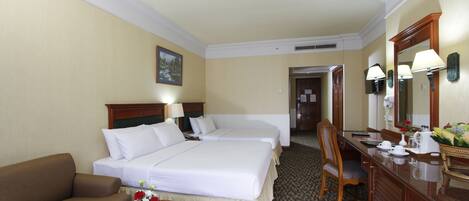 A hotel room with two beds, a sofa, a desk, and a mirror.