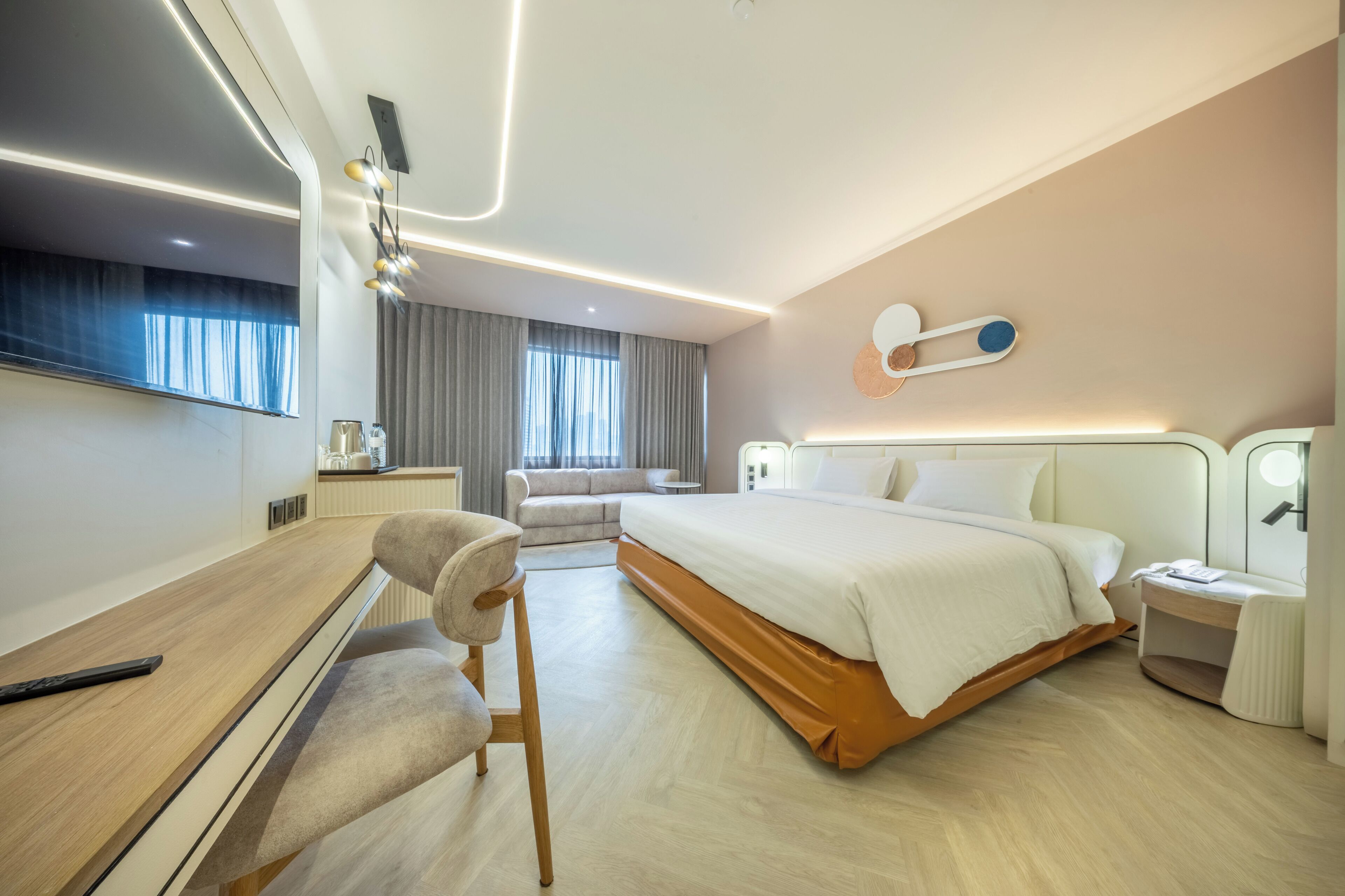 Une chambre d’hôtel moderne équipée d’un grand lit, d’un bureau, d’une chaise et d’un téléviseur.