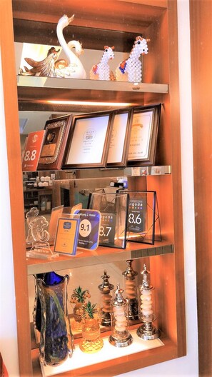 Un espace d’accueil d’hôtel agrémenté de trophées encadrés, d’une liste de prix et d’objets décoratifs.