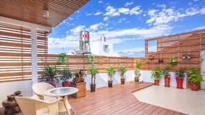 Une terrasse en bois agrémentée de plantes en pot, de chaises en osier et d’une table.