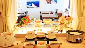 Un comedor con mesas de buffet, que incluye diferentes platos y una olla de cocción lenta.