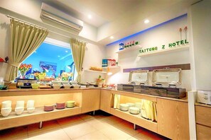 Une chambre d’hôtel avec un buffet de petit-déjeuner, la climatisation et une vue sur le paysage urbain.