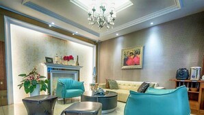 Una sala de estar moderna con chimenea, sillones color turquesa, una mesa de centro y un cuadro en la pared.