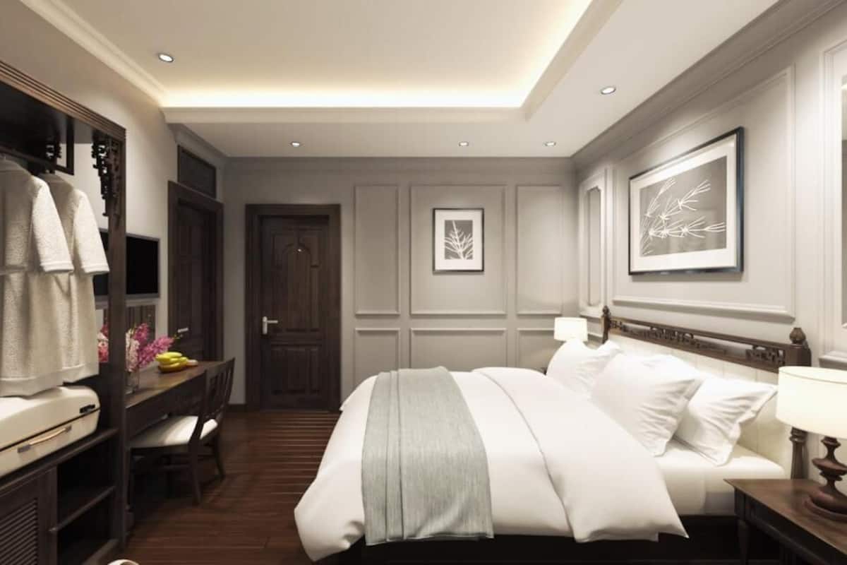 A hotel room with a bed, a desk, a wardrobe, and a mirror.