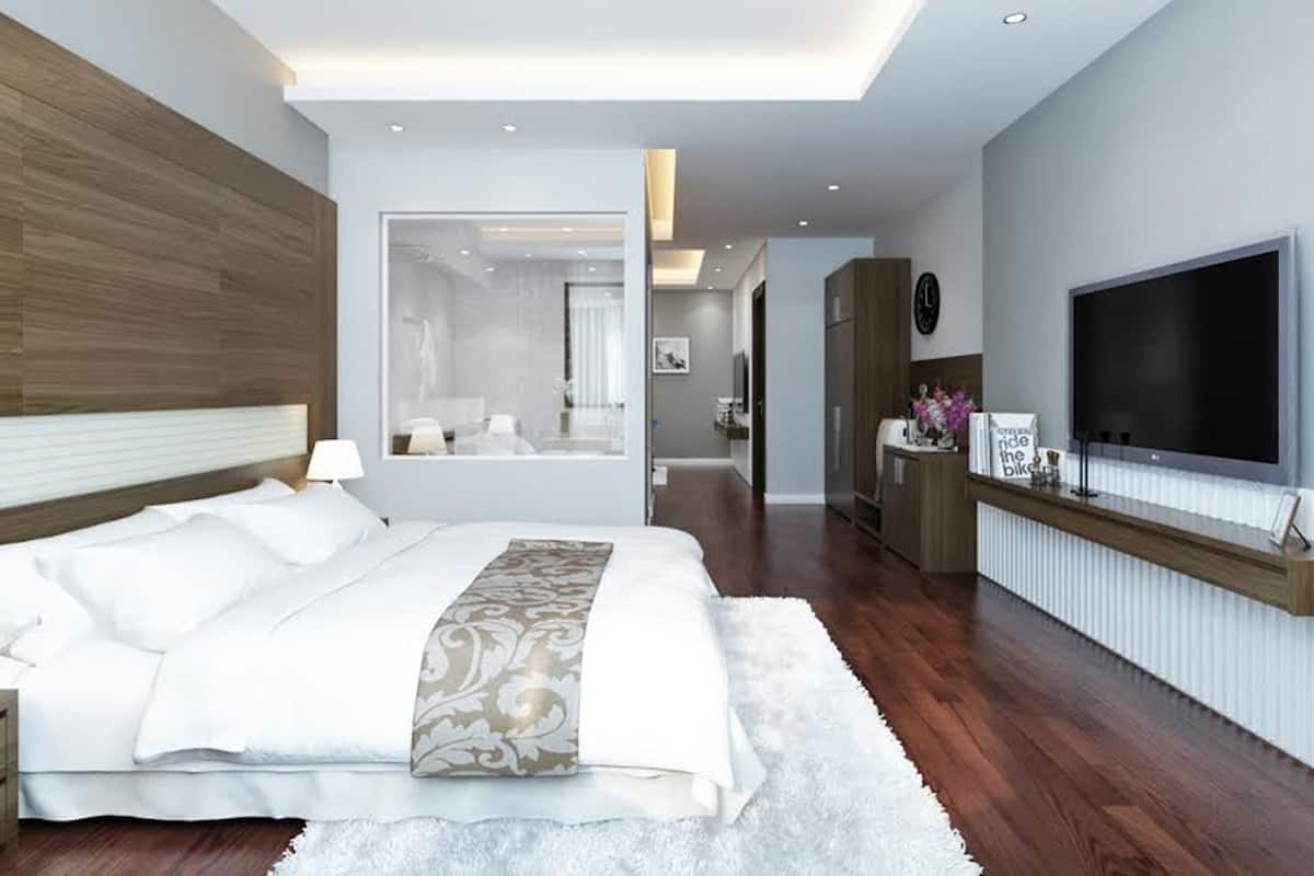 A modern hotel room with a large bed, a TV, and a mirror.
