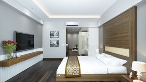 A modern hotel room with a wooden bed, a TV, and a bedside table with a lamp. -  Eco Luxury Hotel Hanoi (Hanoi)