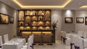 A restaurant with a bar area, white tables, and chairs with purple sashes. -  Eco Luxury Hotel Hanoi (Hanoi)