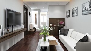A modern living room with a white sofa, a flat-screen TV, and a wooden coffee table. -  Eco Luxury Hotel Hanoi (Hanoi)