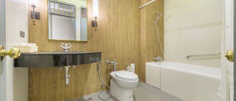 A modern bathroom with a wooden wall, a white toilet, a sink with a black countertop, a bathtub, and a shower.