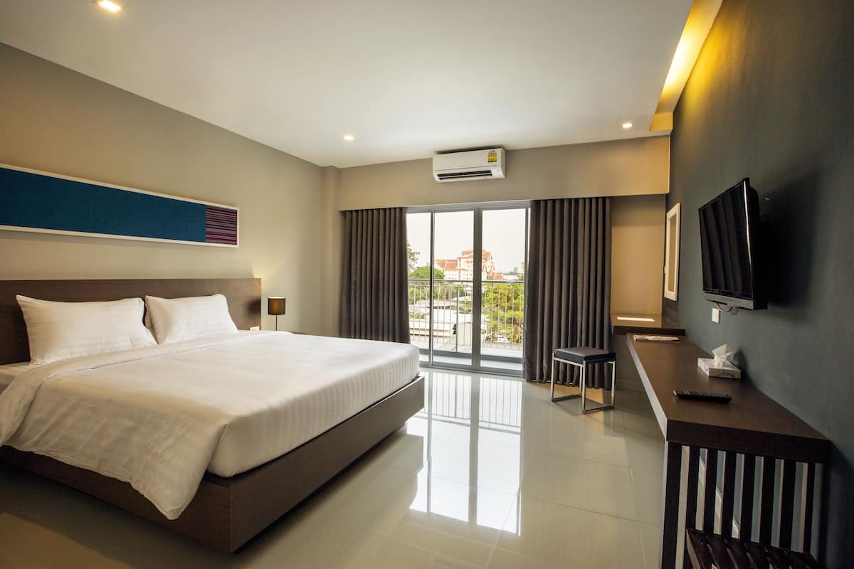 Una habitación de hotel moderna con una cama grande, un escritorio y un televisor.