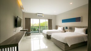 A modern hotel room with two beds, a flat-screen TV, a desk, and a large window with a view of greenery.