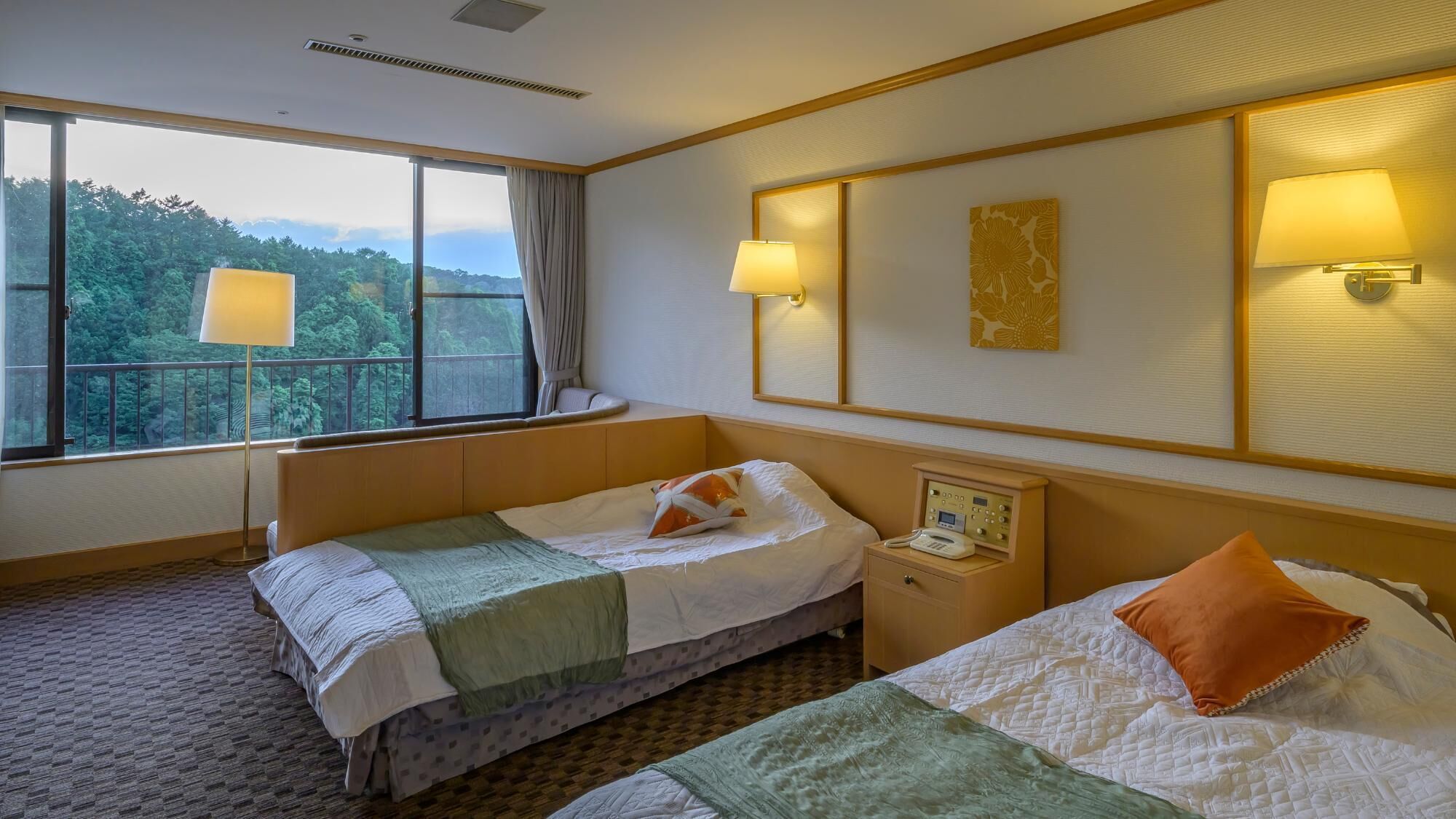 Habitación de hotel con dos camas, una mesita de noche con teléfono, una ventana con vistas a árboles y lámparas fijadas a la pared.