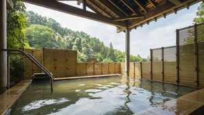A traditional Japanese onsen with a wooden deck and a view of a forested hillside. - Fukuichi (Shibukawa)