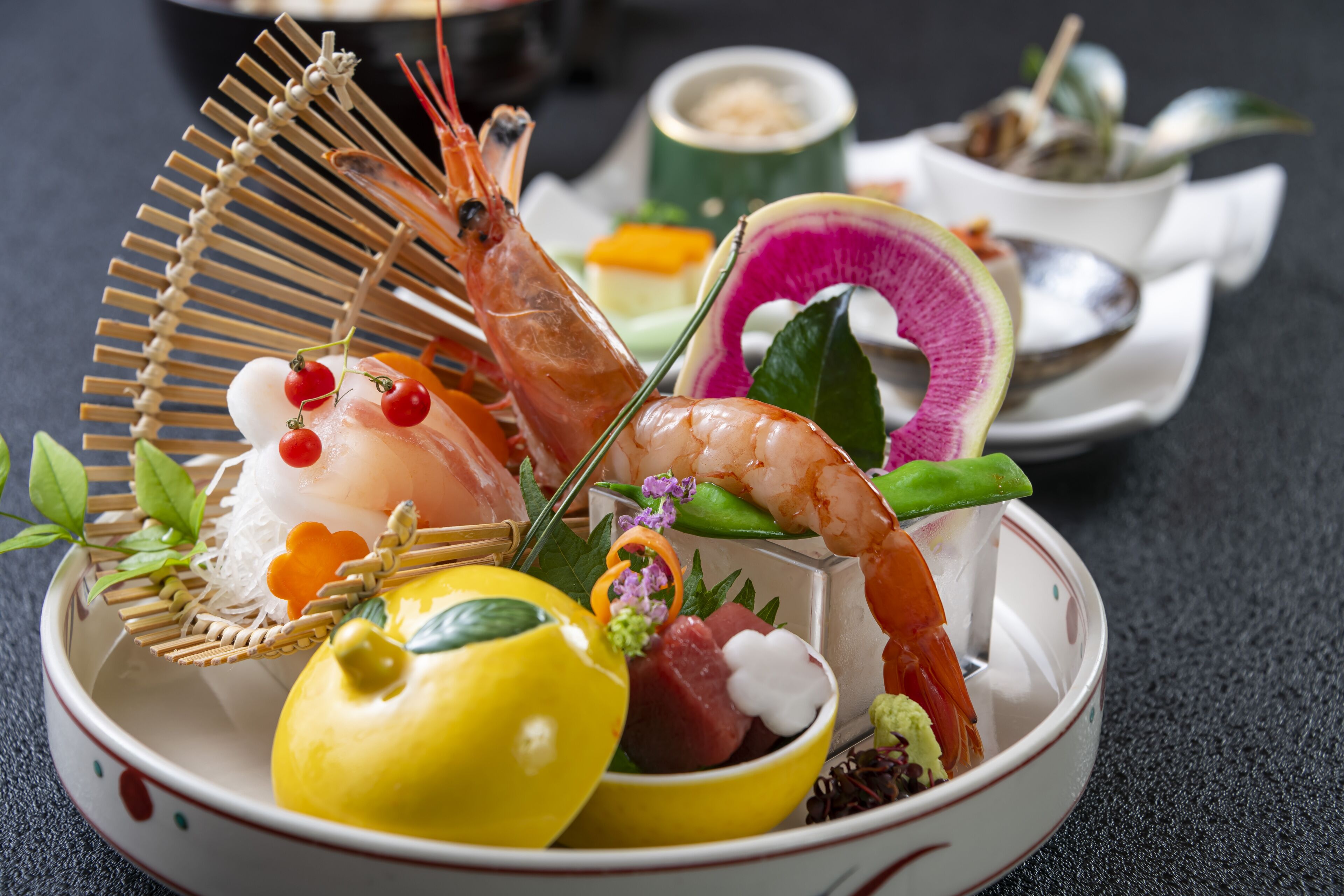 A bowl of assorted seafood and fruits, including shrimp, lemon, and a decorative leaf arrangement.