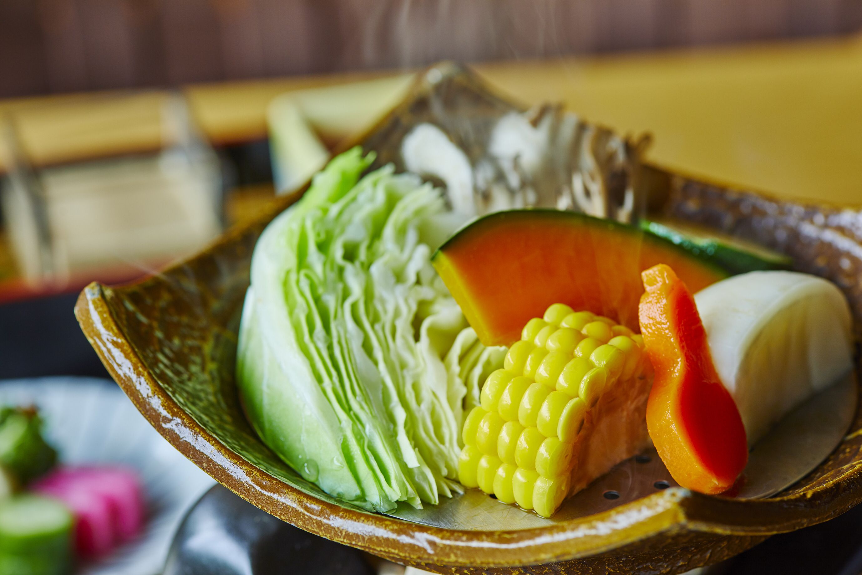 A bowl containing various vegetables including lettuce, corn, and a slice of papaya.