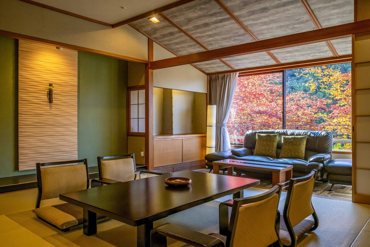 A traditional Japanese-style room with tatami flooring, a low table, and a sofa with cushions.