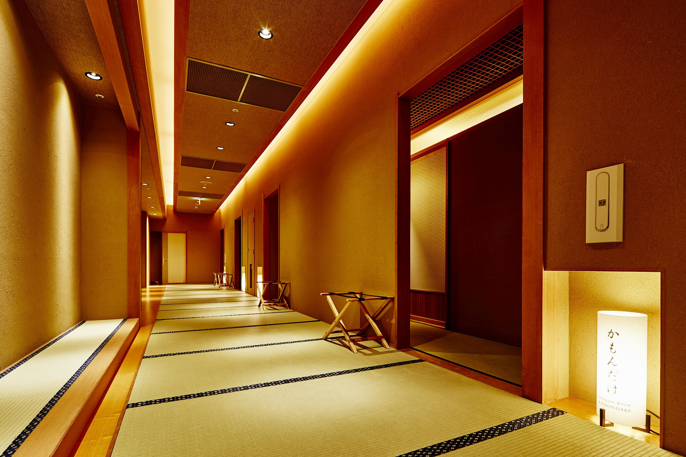 A hotel corridor with tatami mats, wooden flooring, and traditional Japanese decor.