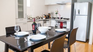 A modern kitchen with a dining table set for two, equipped with wine glasses, plates, and cutlery. - Powder Haven (Kutchan)