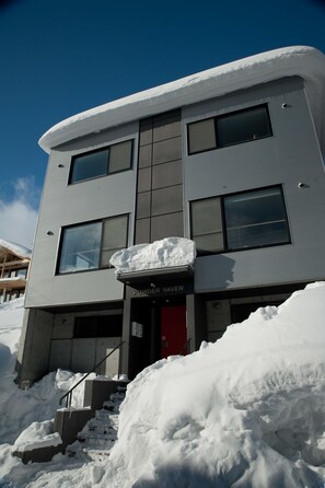 A modern building with a snow-covered entrance and a sign reading "PowderHaven." - Powder Haven (Kutchan)