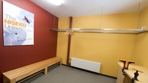 A room with a wooden bench, a radiator, a clothes drying rack, and a poster on the wall. - Powder Haven (Kutchan)