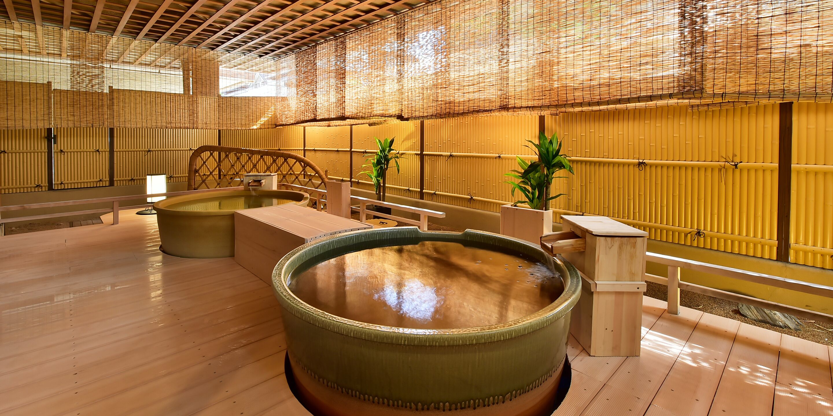 A traditional Japanese onsen with wooden floors, tatami mats, and a large hot spring bath.