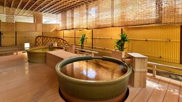 A traditional Japanese onsen with wooden floors, tatami mats, and a large hot spring bath.
