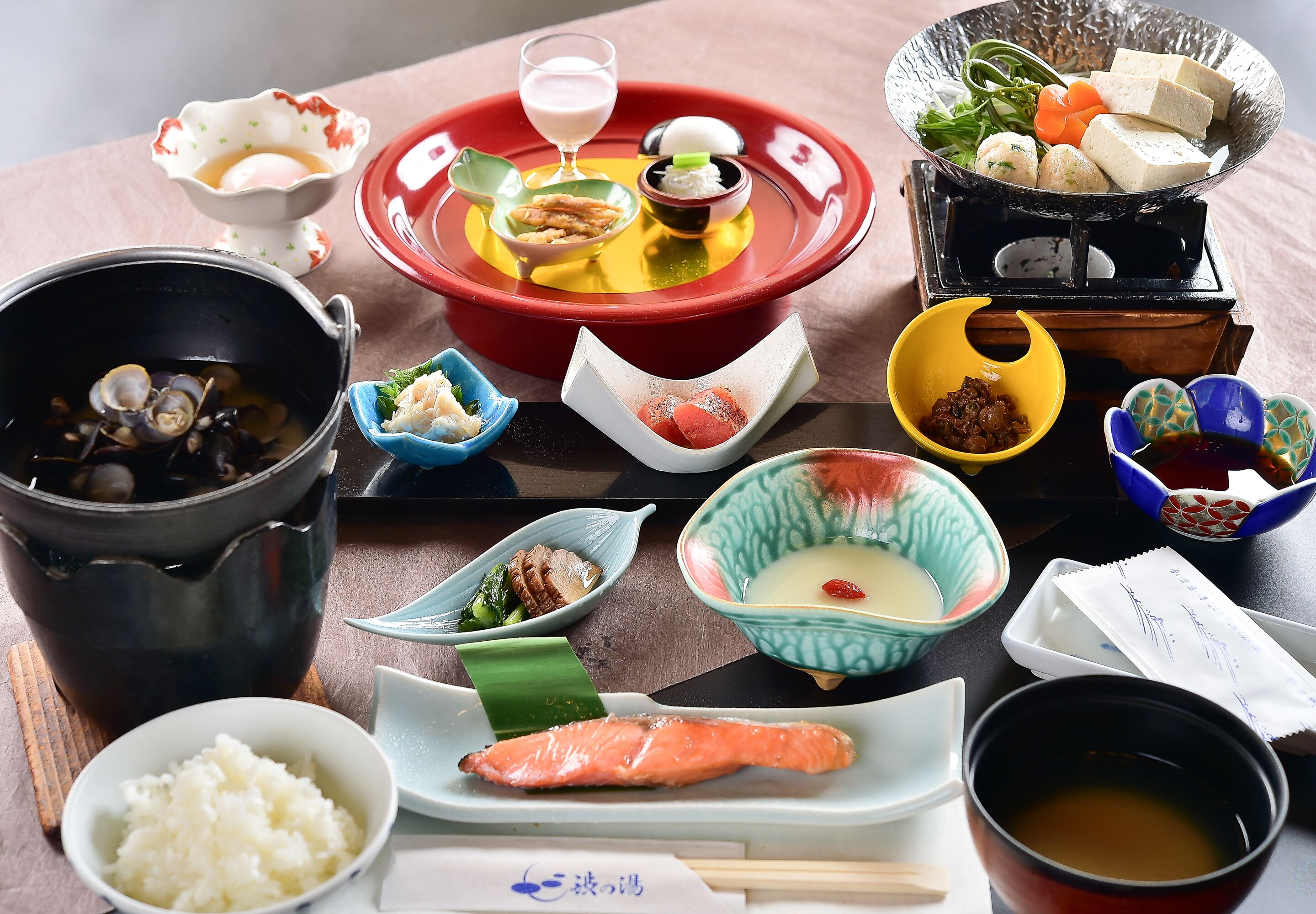 A variety of Japanese dishes including sushi, sashimi, and a hot pot, arranged on a table.