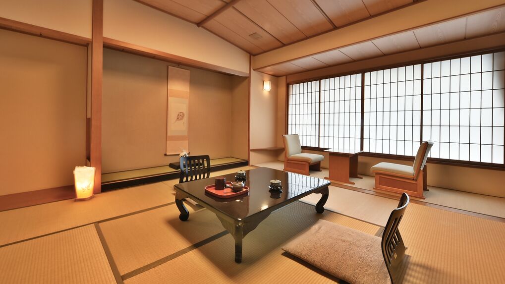 A traditional Japanese room with tatami flooring, a low table with a tray, and a sliding door with a grid pattern.