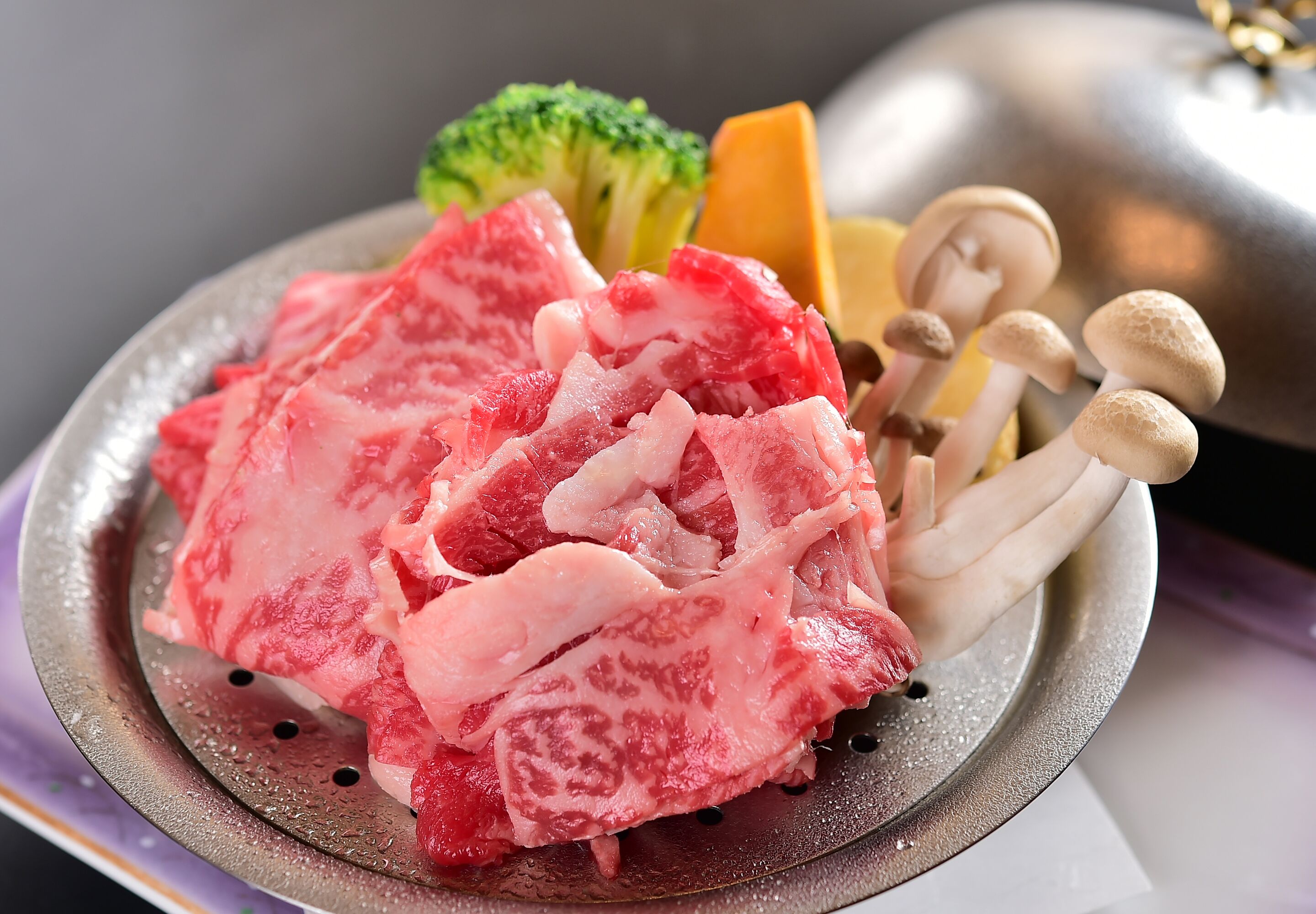 A plate with raw meat, mushrooms, and vegetables.